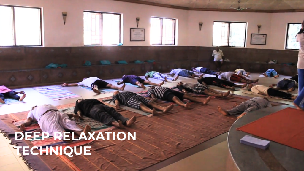 Participants lying on their backs on mats during a group deep relaxation session in an Indian Nature Cure hospital.